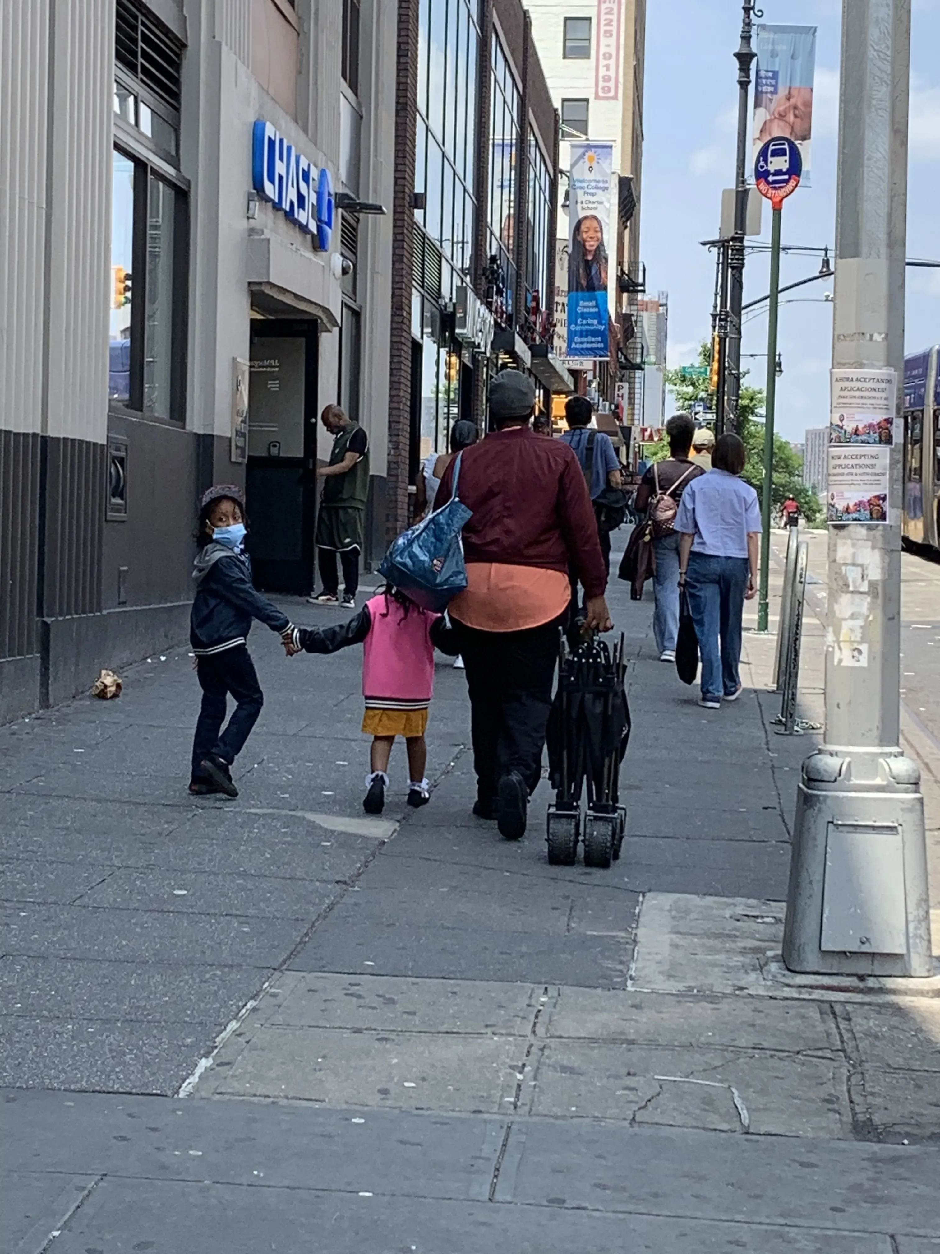 Woman walks down the street with her children and one looks back